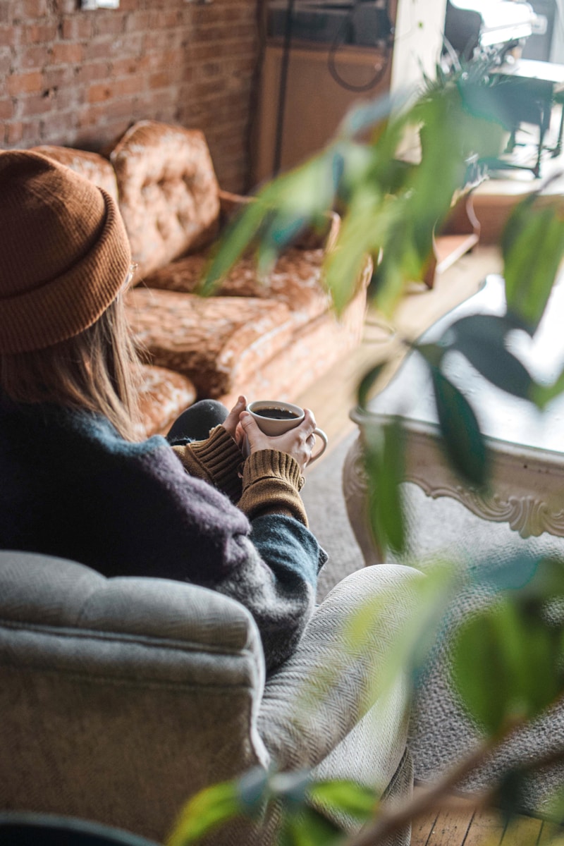 a woman sitting on a couch holding a cup of coffee